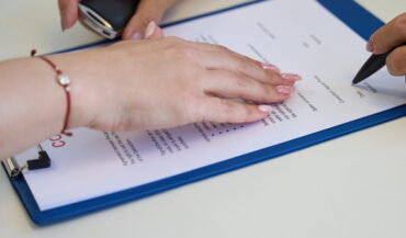 Process of signing documents on the purchase and sale of a car, the manager indicates the place of signature