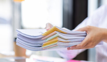 close-up-of-business-hands-working-in-stacks-of-pa-2025-02-22-16-15-29-utc